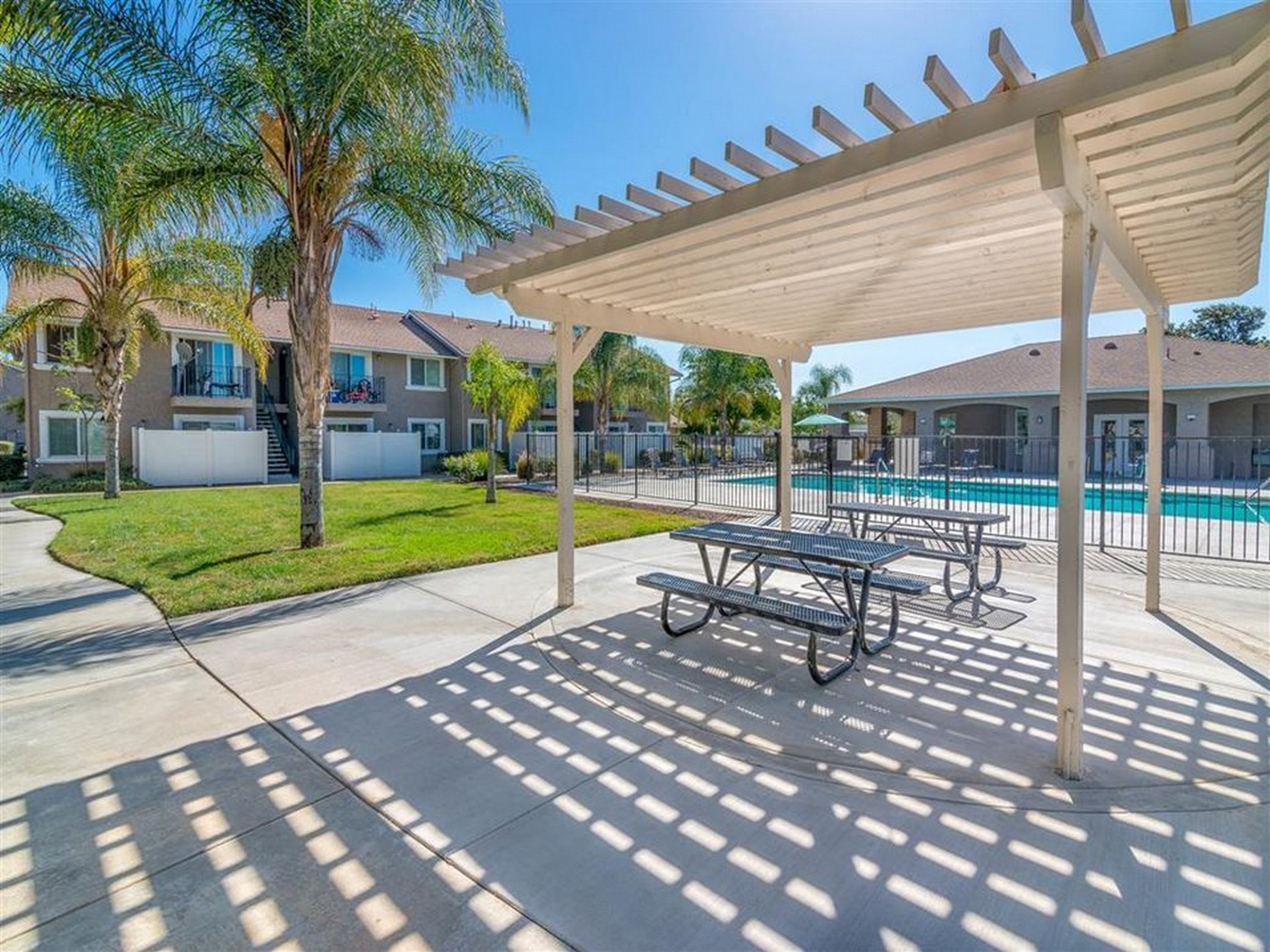 a swimming pool with picnic tables under a canopy